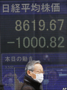 A man walks past a stock price board in Tokyo