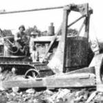Gene Fiducia operating D7 angle dozer somewhere in Normandy June 1944. Demolishing stone house for gravel to construct and repair bombed roads.
