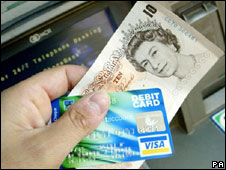 Someone holding a debit card and cash
