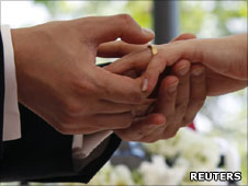 One hand putting wedding ring on another hand