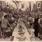 This is a street party on VE day held at Wesley Grove Portsmouth. My parents are in the forground my father to the right wearing his office suit my mother is at the front on the left.
