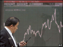 Homem passa diante de painéis mostrando alta do mercado japonês
